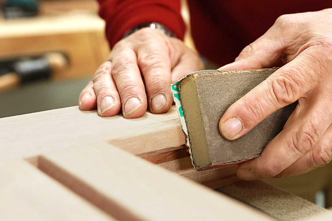 Nahaufnahme von den Händen eines Stöckel Mitarbeiters, der gerade Holz abschleift.