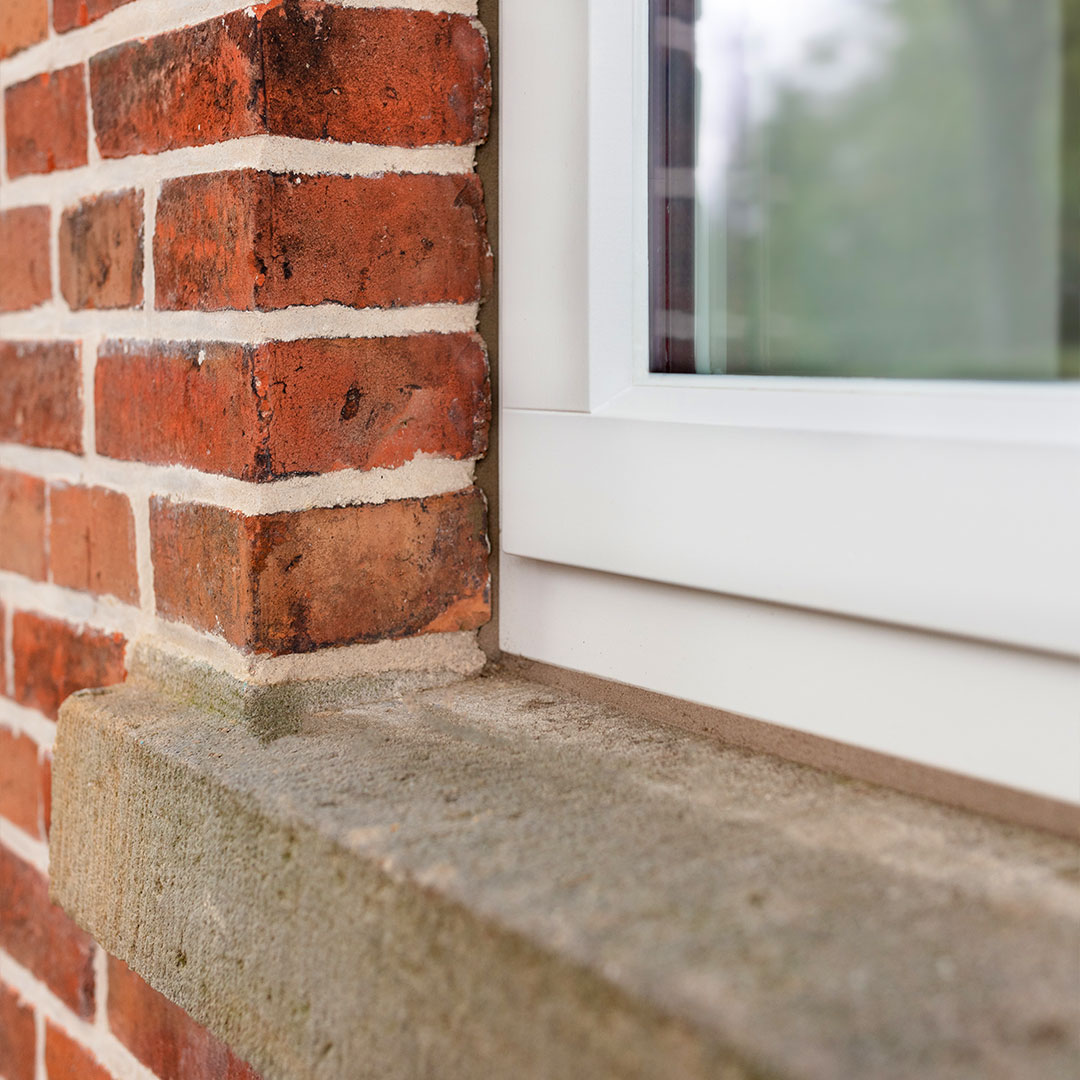 Nahaufnahme eines weißen Fensters in einem Ziegelsteinhaus.