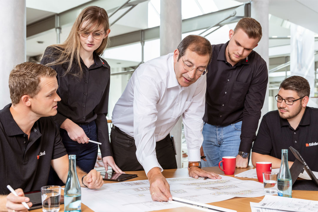 Eine Gruppe von Stöckel Mitarbeitern bespricht ein Projekt.